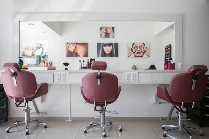 Salón de peluquería, espejo, fotos, utensilios de belleza, sillas rosadas