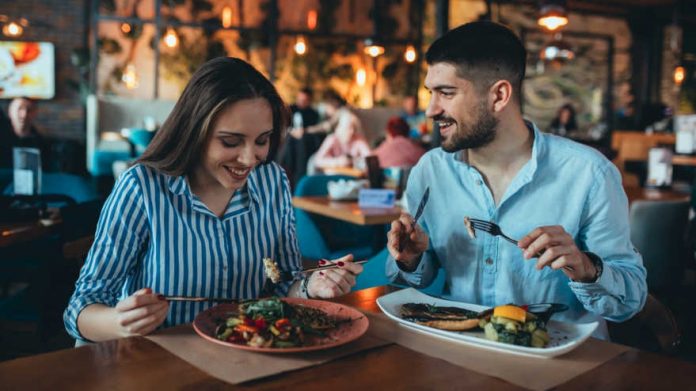 Hombre y mujer en restaurante con dos platos de comida