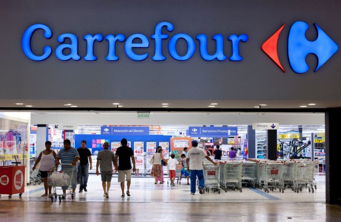 Fachada de tienda Carrefour con personas en la entrada