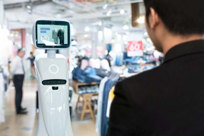 Hombre en tienda por departamento al frente de un robot de atención al cliente