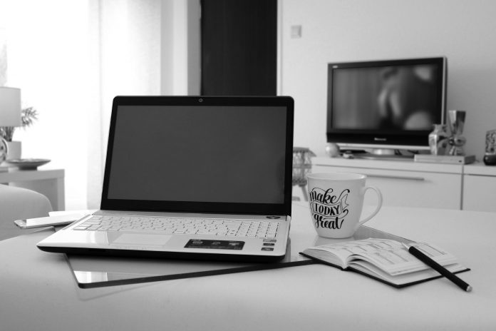 Cuarto con escritorio, lapto , taza de café y al fondo televisor
