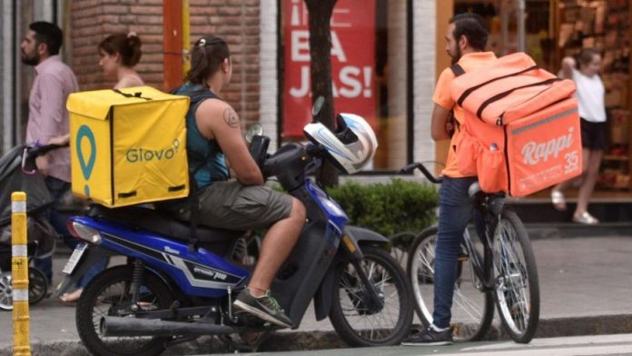 Avenida, hombres en moto y bicicleta con cavas de delivery