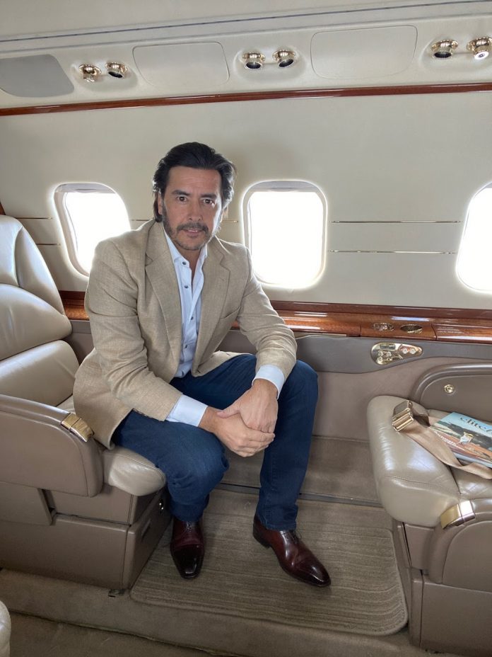 Hombre con traje sentado en el sofá del interior de un avión