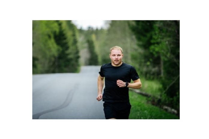 Hombre en ropa deportiva negra corriendo en un bosque