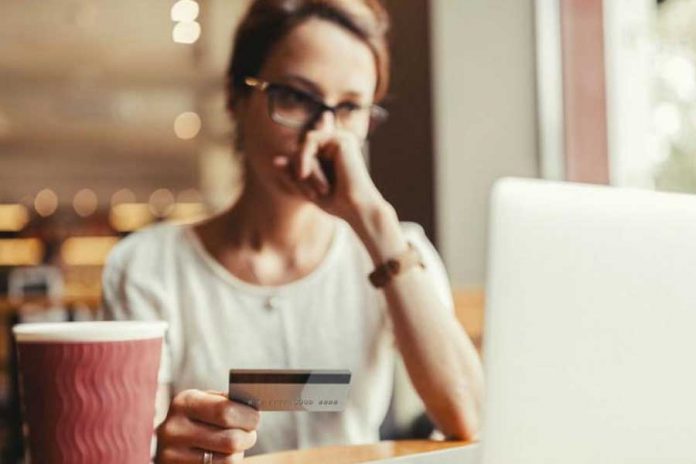 Mujer de lentes frente a laptop con tarjeta de banco