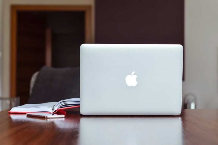MacBook plateada sobre una mesa, agenda y celular