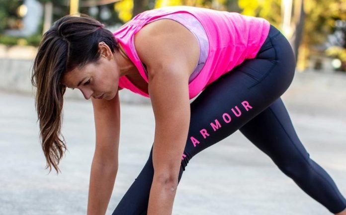 Mujer con ropa deportiva rosada y negra practicando ejercicio