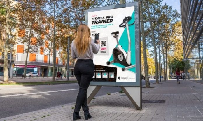 Mujer en avenida tomándole foto a una publicidad