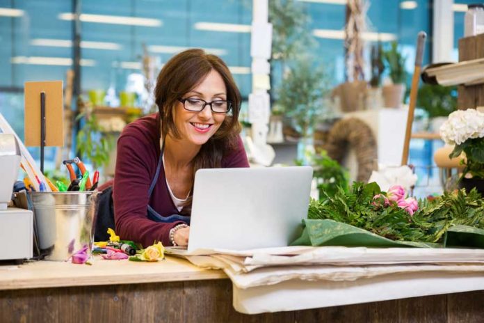 Mujer con laptop sobre mostrador y plantas decorativas