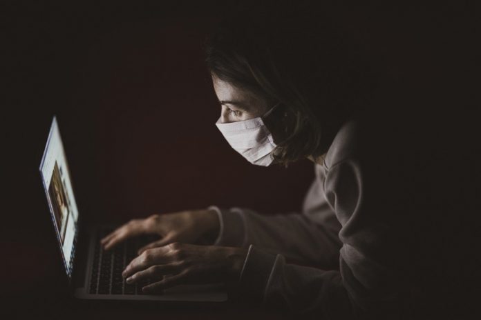 Mujer con tapaboca trabajando con laptop