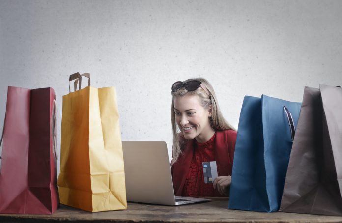 Mujer con laptop y bolsas de colores