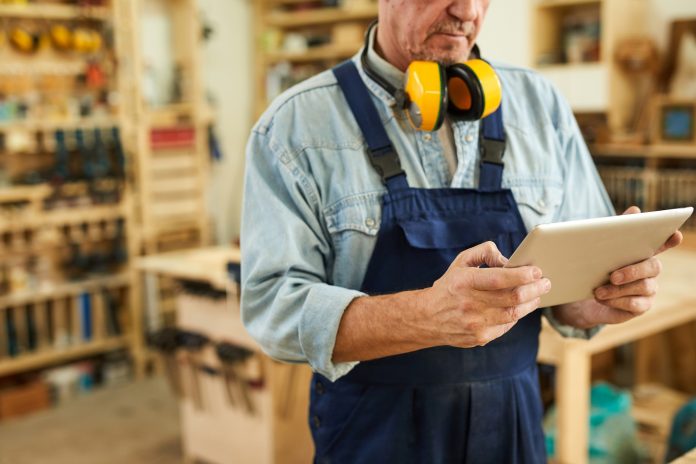 Hombre con braga azul, audífonos amarillos y table en las manos en una tienda
