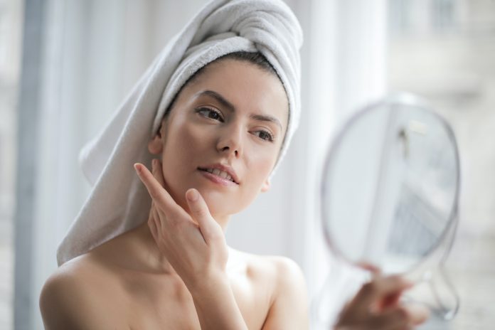 Mujer con toalla en la cabeza mirándose en un espejo