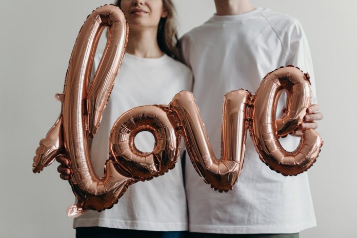 Personas vestidas de blanco sosteniendo unos globos con la frase love