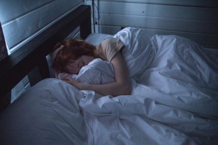 Mujer durmiendo en cama con sabanas blancas