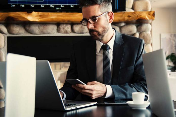 Interior de oficina, hombre con traje y tarjeta de banco en las manos, mesa con laptop y taza de café
