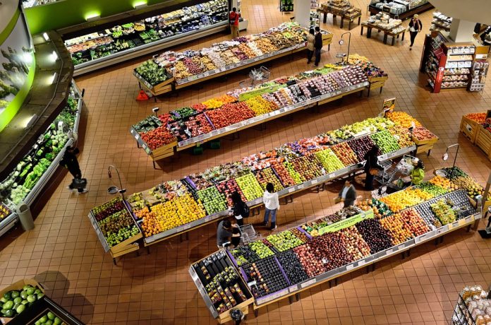 Interior de supermercado, anaqueles y estanterías con productos personas alrededor