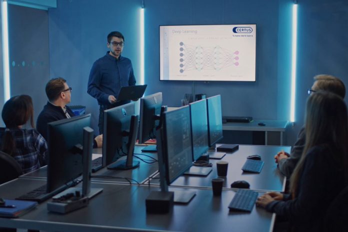 Personas alrededor de mesa con computadoras en una reunión