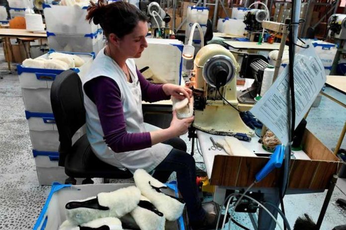 Mujer sentada trabajando en maquina industrial haciendo zapatos