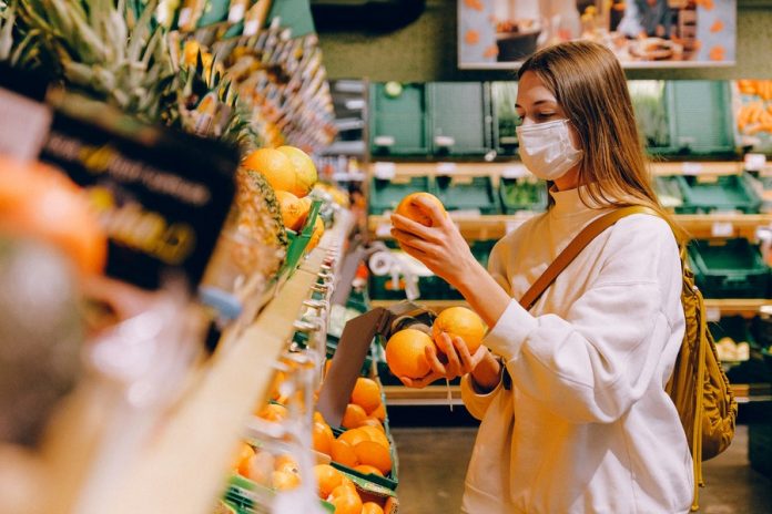 Interior de mercado, estantes con productos. mujer sosteniendo frutas