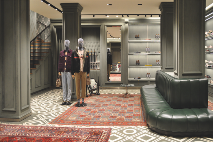 Interior de tienda Gussi, estantería con carteras y accesorios de damas, maniquí con ropa de caballeros