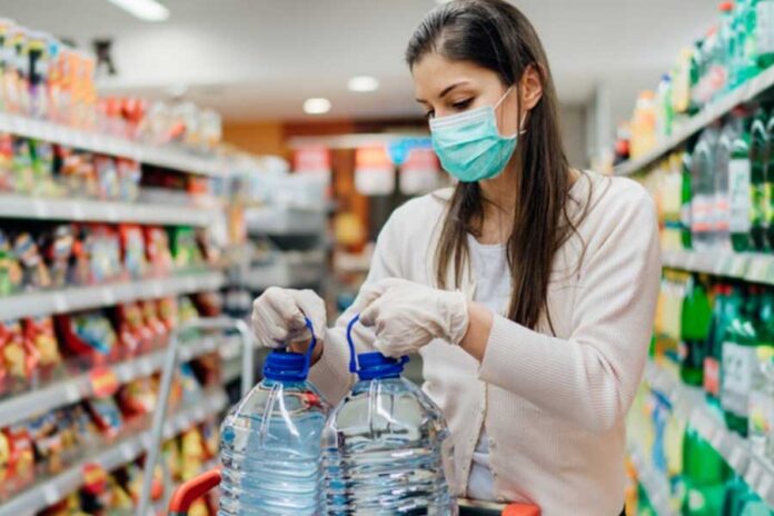 Mujer toma dos potes de agua de 5 litros en un supermercado merchandising
