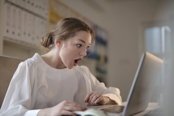 Mujer observando laptop con la boca abierta