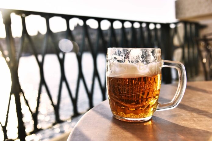 Vaso de cerveza sobre una mesa, en un balcón durante la tarde. Cervecería