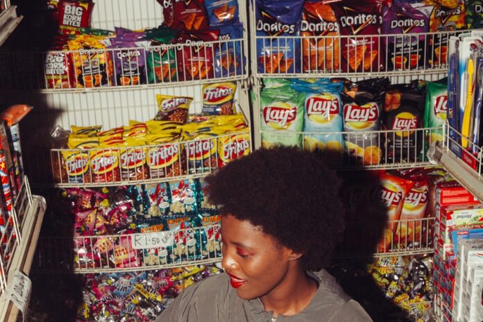 Interior de tienda, estantes con checherias, mujer observando
