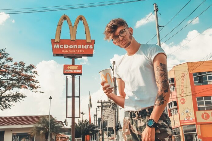 Hombre tatuado posa frente a un local de McDonald's