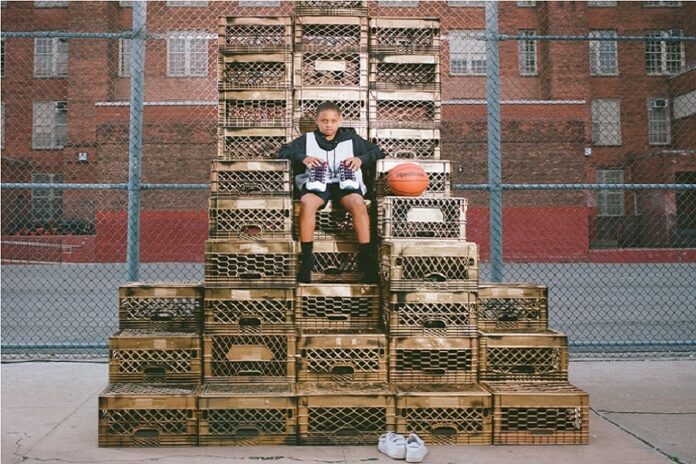 Cancha, niño sentado con zapatos deportivos y balón de basquet