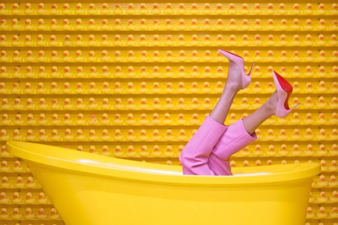 Persona en bañera amarilla con pantalón y zapatos rosados