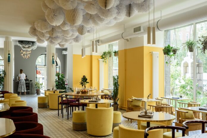 Restaurante con sillas, meses y paredes amarillas