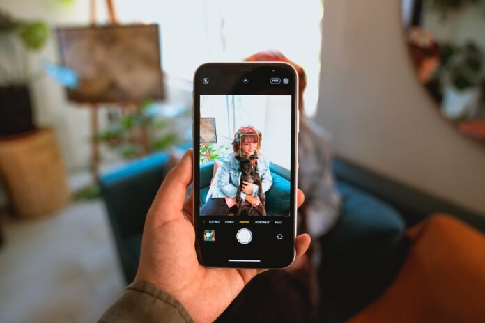 Mujer posa con su perro ante la cámara de un teléfono celular