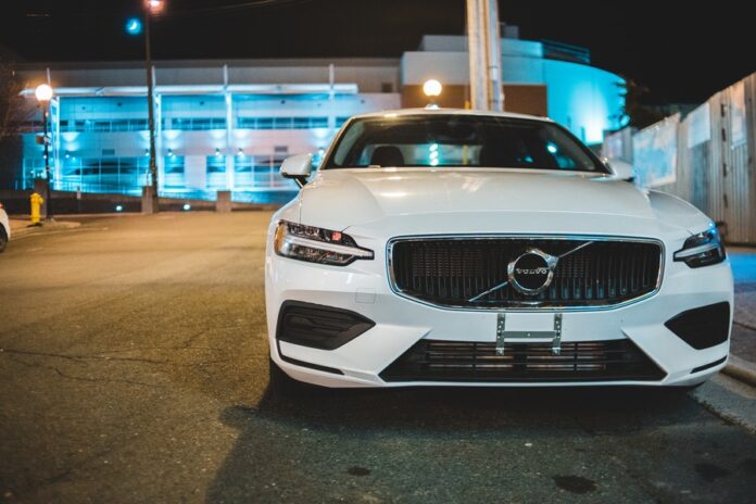 Carro marca Volvo de color blanco en un estacionamiento de noche. Industria automotriz. automóviles