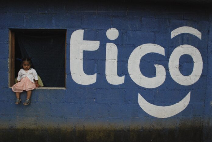 Pared pintada con el logo de Tigo y una niña sentada en una ventana