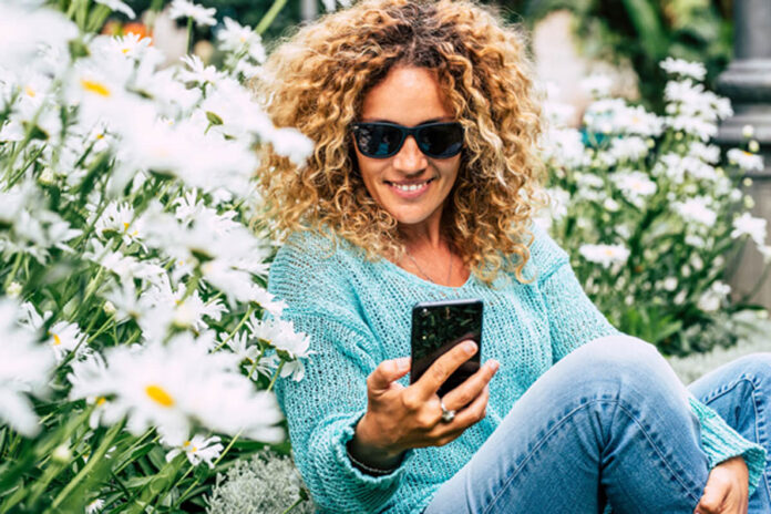 mujer sentada sobre flores viendo el celular