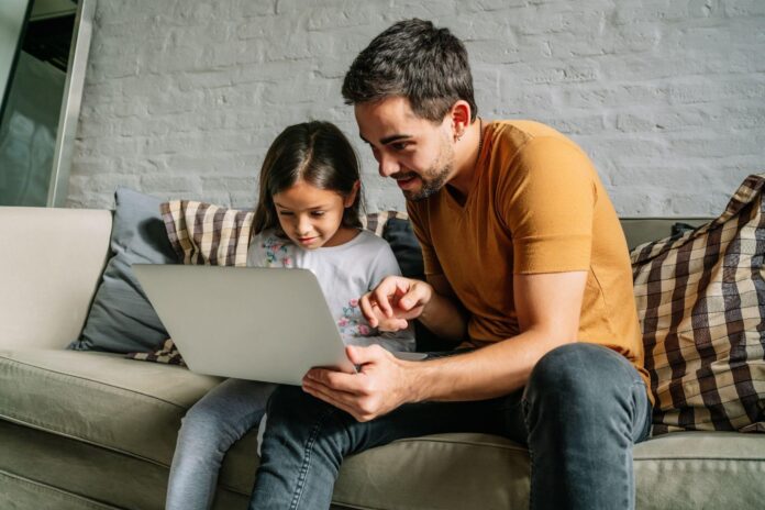 padre e hija en sofa mirando la laptop