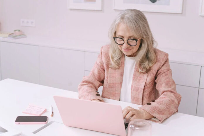 mujer adulta trabajando con laptop rosada