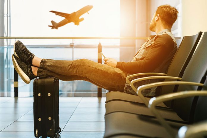 Hombre en aeropuerto esperando vuelo para ir de vacaciones